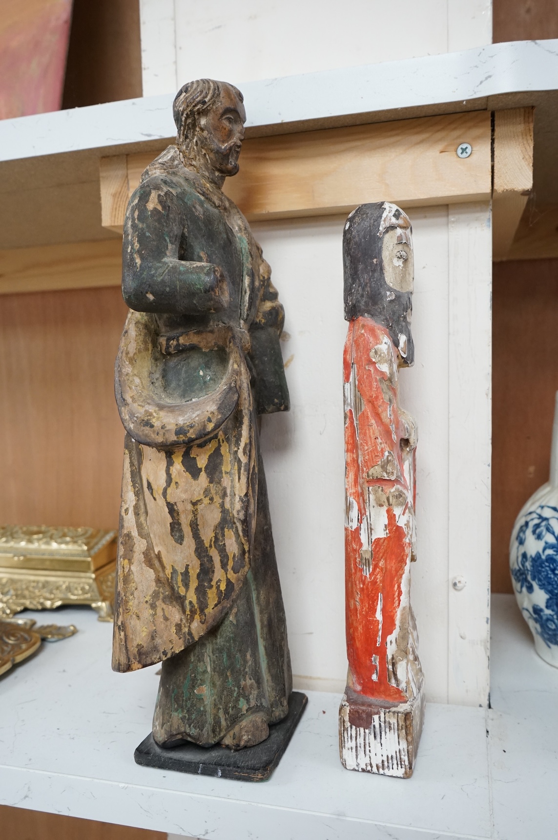 An antique carved wood figure of a Saint, traces of old paint and another figure, largest 36cm high (2)